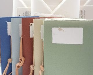 Confezione regalo in carta di Amalfi contenente carta da lettere con buste associate e un quaderno rilegato a mano con copertina tra un colore a scelta.