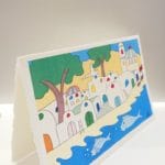 Cartoline su carta di Amalfi colore avorio dal design pieghevole. Nell'immagine, l'illustrazione rappresenta una spiaggia della costiera amalfitana in stile ceramica vietrese.