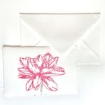 Table markers for receptions in handmade paper and matching ivory envelope. On the place card is engraved, in a handmade way, a Dahlia with pink petals.