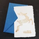 Amalfi paper Christmas cards with handmade gold embossed decoration. The decoration depicts a Christmas reindeer with Marry Christmas written in English at the bottom.