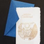 Biglietti natalizi in carta di Amalfi realizzati con dorature a rilievo. In copertina l'illustrazione di un camino acceso con le tipiche calze di Natale.